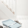 Matty changing tray in soft blue with white strap on a white wooden floor surrounded by grey folded towels