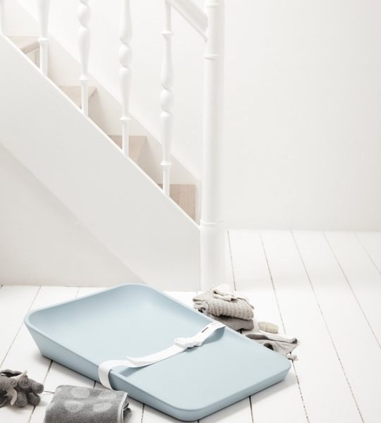Matty changing tray in soft blue with white strap on a white wooden floor surrounded by grey folded towels