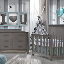baby room with grey and white striped walls with blue hearts and framed letters with wooden floors, dark wood double dresser and crib with blue sheets, a blue ottoman