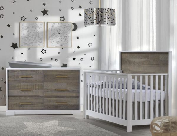 White bedroom with moon and star decals on walls, a white crib and double dresser with dark brown bark facades featuring a grey matty changing tray