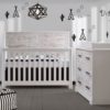 White bedroom with teepee and cactus decals on walls, a white crib and double dresser with white bark facades