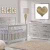 Pink baby nursery with framed golden heart and vibe letters, featuring a white crib and double dresser with white bark facades, a matty changing tray in light pink