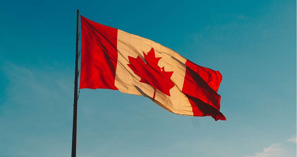 canada flag in the wind over blue skies